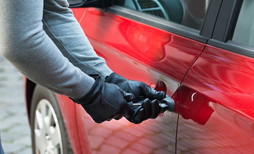 Ratgeber Auto-Diebstahl - Männerhände in Handschuhen versuchen Auto aufzubrechen