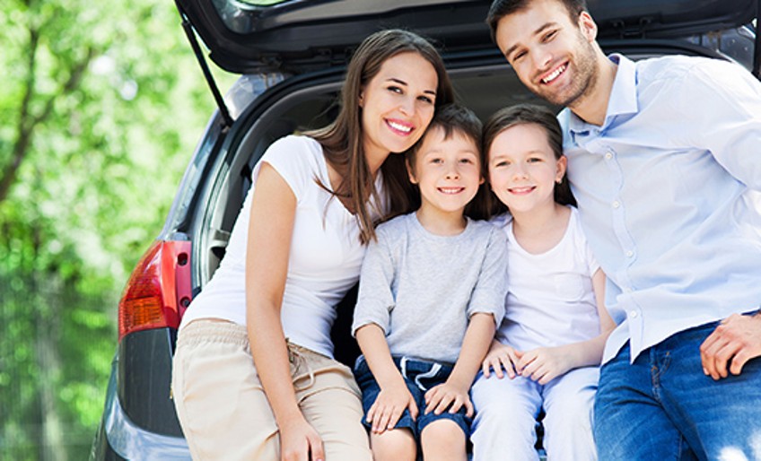 Ratgeber Autofahren mit Kind - Vierköpfige Familie sitzt im Kofferraum eines Autos
